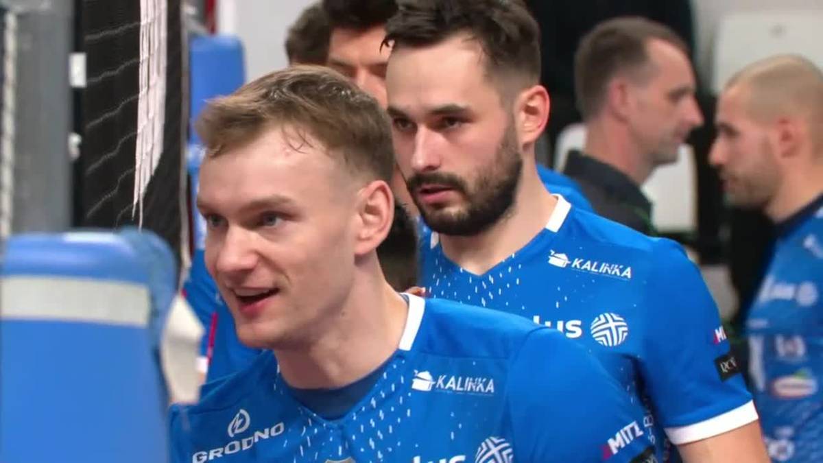 Grupa siatkarzy w niebieskich strojach sportowych, jeden z nich uśmiecha się.