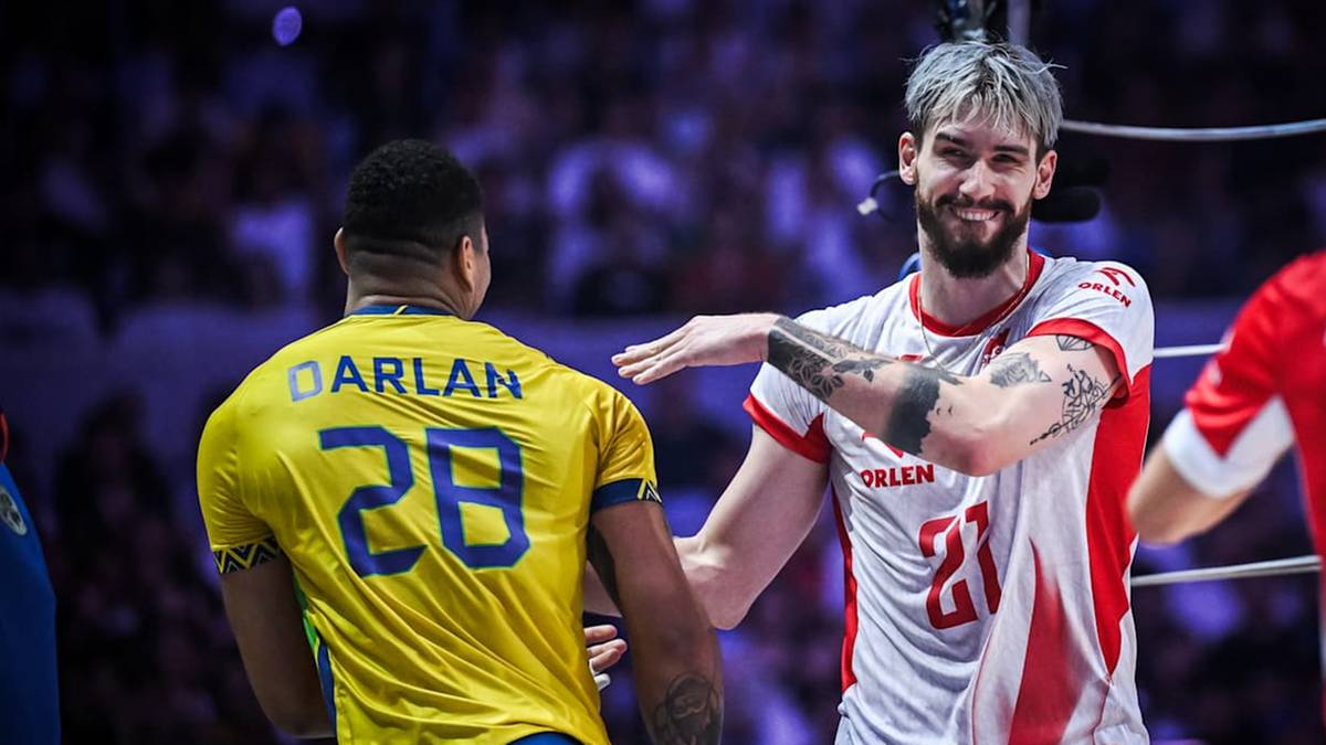 Dwóch siatkarzy na boisku, jeden w żółtej koszulce z napisem "DARLAN 28", drugi w białej koszulce z czerwonymi elementami i numerem "21". Obaj gestykulują rękami, prawdopodobnie w trakcie rozmowy.