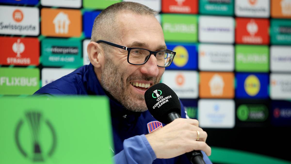 Trener Marek Papszun uśmiecha się do mikrofonu podczas konferencji prasowej.