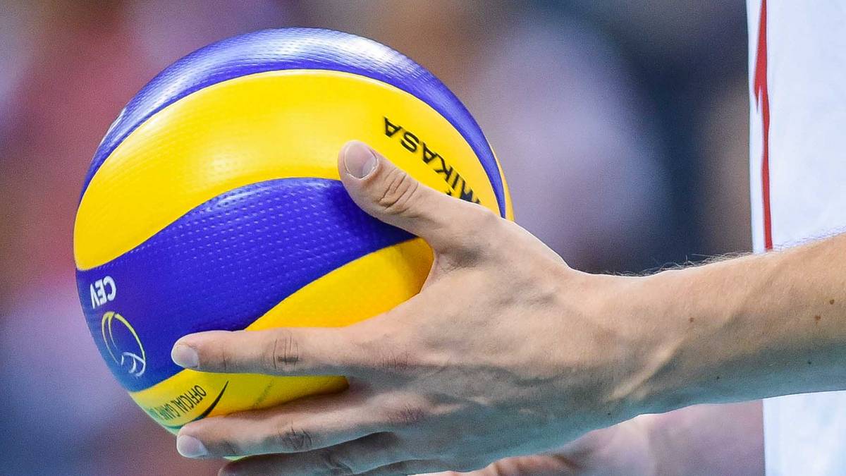Siatkarz trzymający piłkę do siatk&oacute;wki.