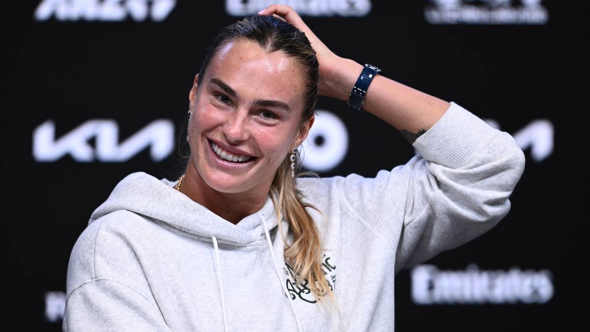 Uśmiechnięta Aryna Sabalenka z dłonią na włosach.