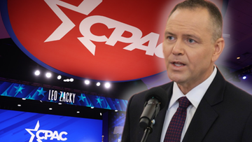 Mężczyzna w garniturze m&oacute;wi do mikrofonu na tle sceny z logo CPAC.