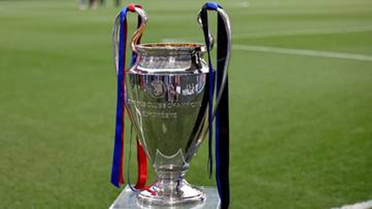 Trofeum Ligi Mistrzów UEFA ozdobione wstążkami w kolorach niebieskim, czerwonym i czarnym, stojące na tle murawy piłkarskiej.