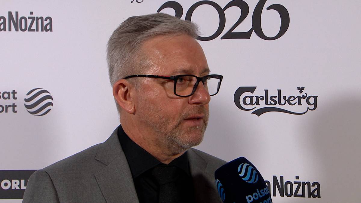 Jerzy Brzęczek w okularach i garniturze udziela wywiadu przed białym tłem z logotypami.