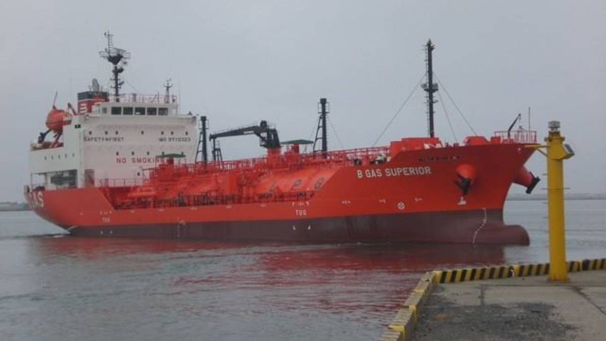 Czerwony tankowiec z białym nadbudówką, pływający po wodzie, z widocznym napisem "B GAS SUPERIOR" na burcie.