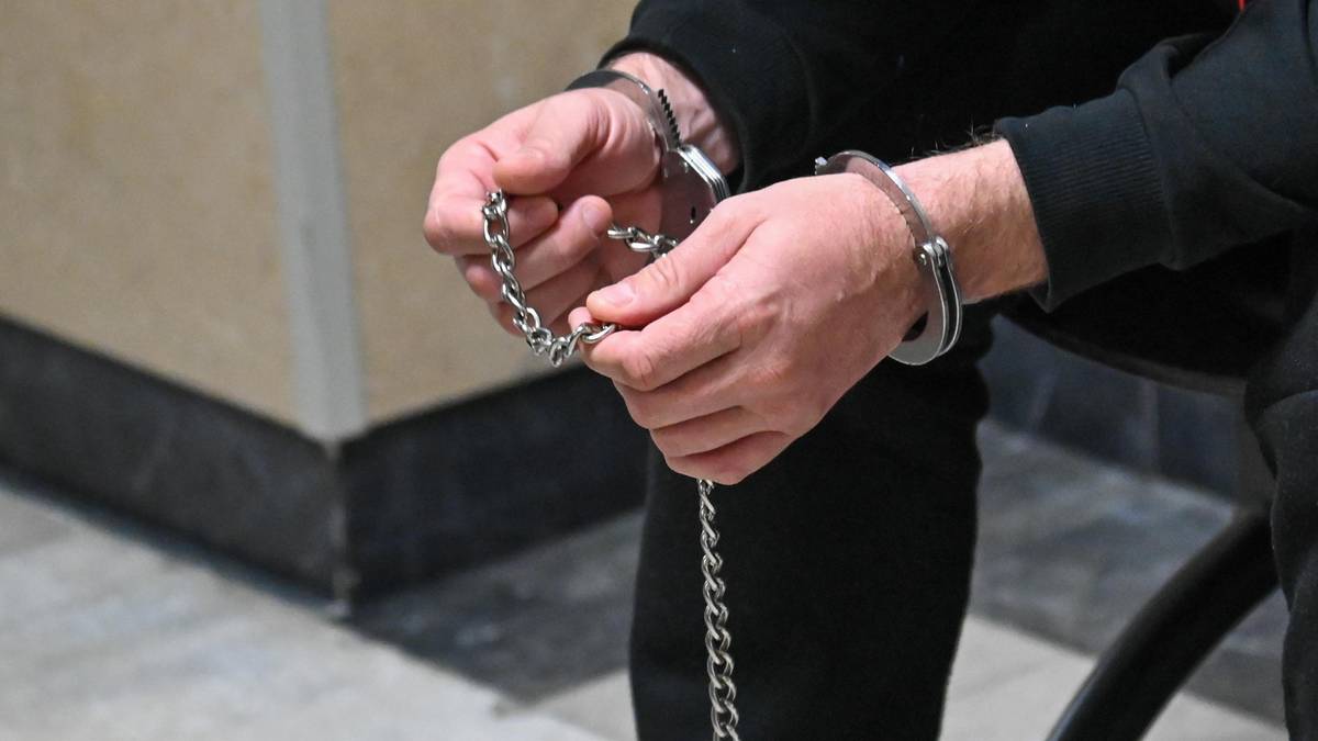 Dłonie osoby z zapiętymi kajdankami połączonymi łańcuchem.