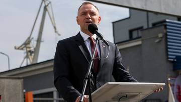 Karol Nawrocki przemawia za m&oacute;wnicą na tle stoczniowych dźwig&oacute;w.
