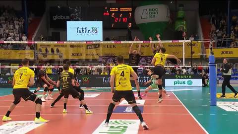 Gracz w ż&oacute;łtej koszulce wykonuje atak podczas meczu siatk&oacute;wki.