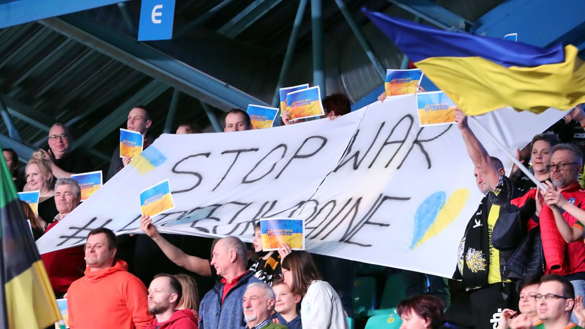 Grupa osób trzyma transparent z napisem "STOP WAR" i flagami Ukrainy.