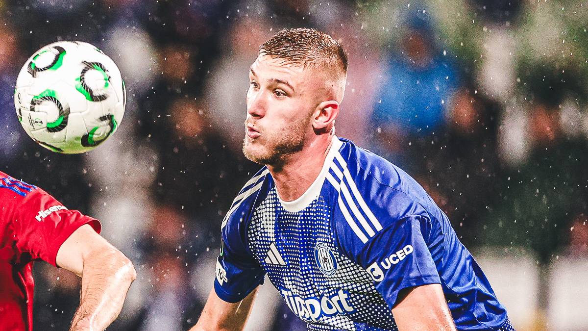 Dwóch piłkarzy walczy o piłkę na boisku podczas meczu.