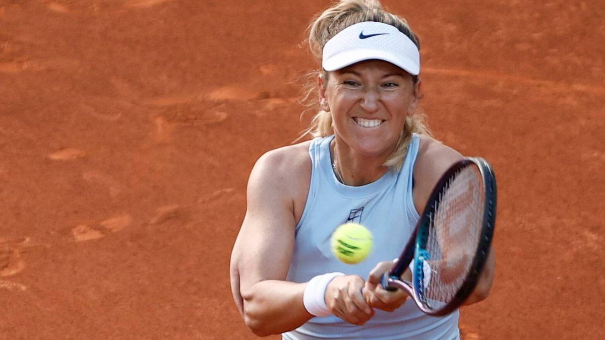 Tenisistka podczas meczu na kortach Rolanda Garrosa, skupiona i wybijająca piłkę rakietą.