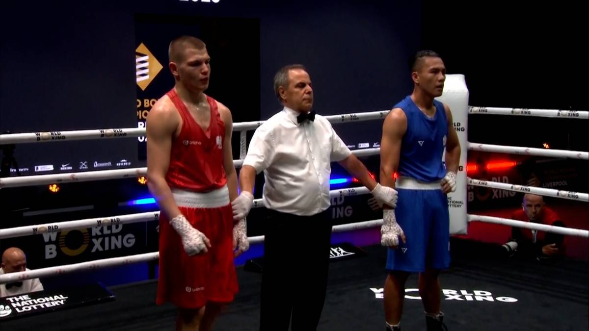 Trzech mężczyzn w ringu bokserskim. Dwóch bokserów po bokach i sędzia pośrodku.