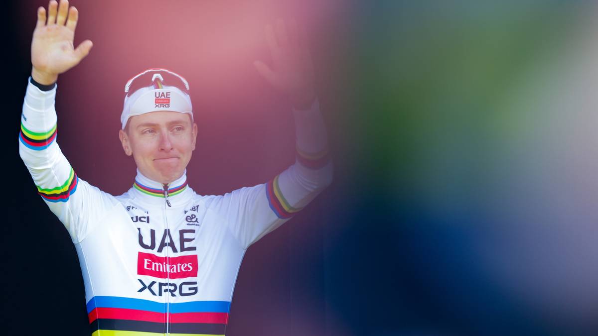 Tadej Pogacar w koszulce kolarskiej z podniesionymi rękami.