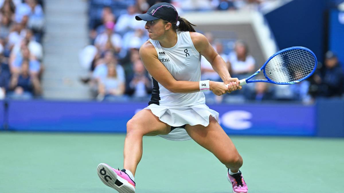 Iga Świątek w akcji podczas meczu tenisowego, odbijająca piłkę rakietą.