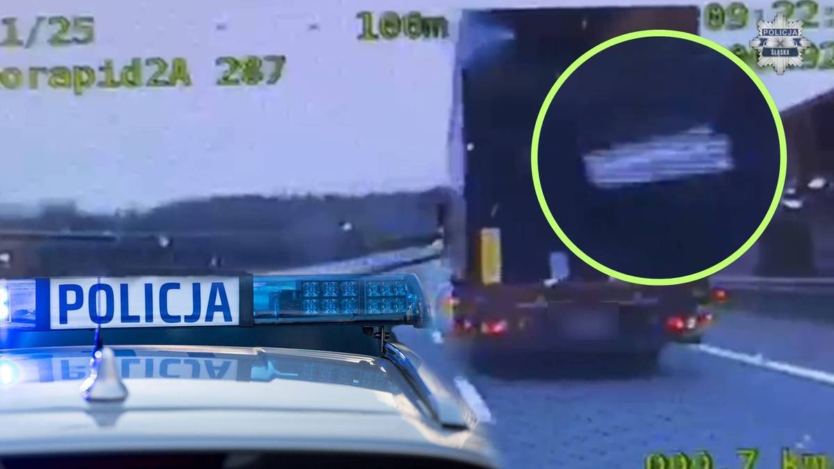 Fragment radiowozu policyjnego z włączonymi sygnałami świetlnymi na autostradzie A4, przed którym spadła zbita warstwa śniegu z dachu naczepy ciężarówki.