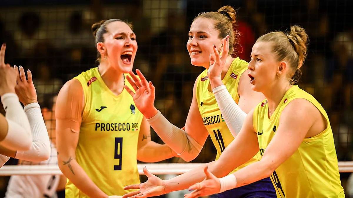 Trzy siatkarki w żółtych strojach z napisem "PROSECCO" krzyczą z radości na boisku.