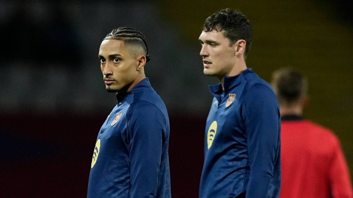 Piłkarze w niebieskich strojach na boisku, jeden z nich patrzy w stronę kamery.