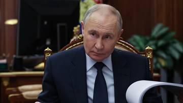 Vladimir Putin siedzący przy biurku z dokumentami