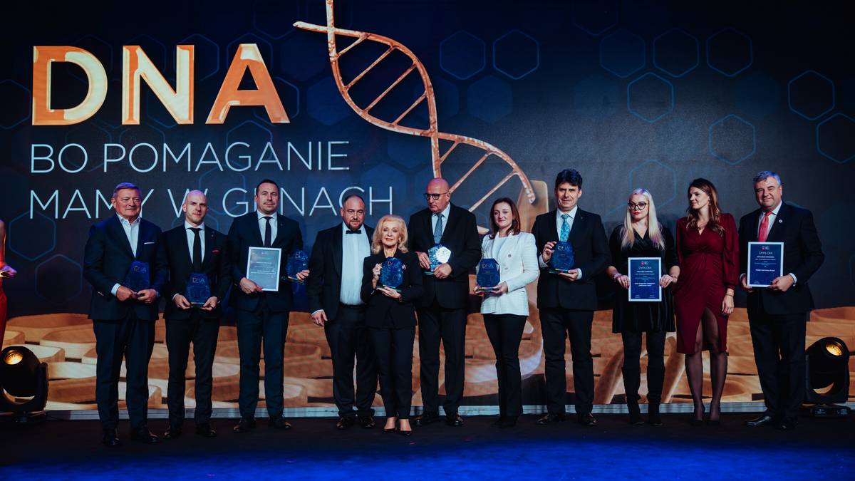 Grupa osób na scenie odbiera nagrody podczas ceremonii wręczenia dyplomów lub statuetek.