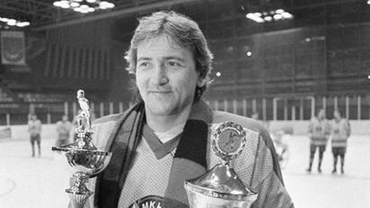 Mężczyzna w stroju hokejowym trzyma dwa puchary.