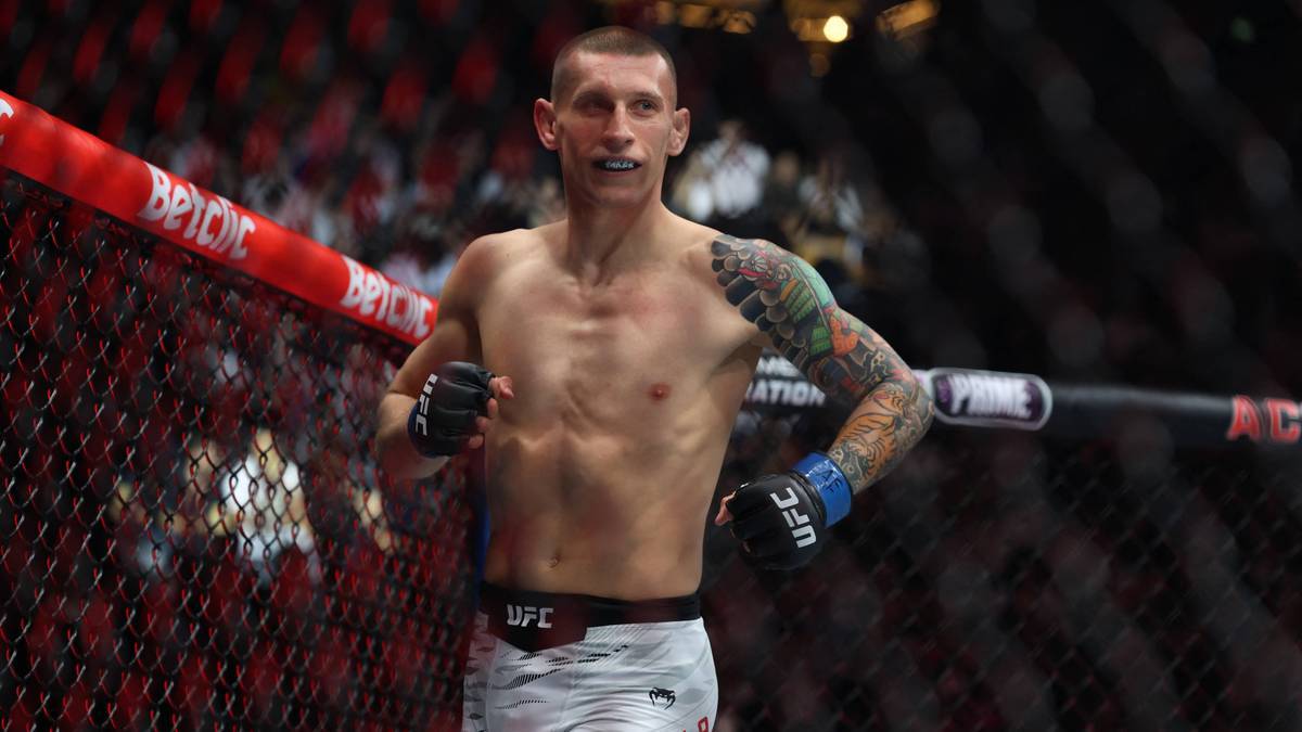 Adam Ruchała w ringu UFC, z rękawicami bokserskimi i widocznymi tatuażami na ramieniu.