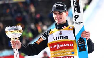 Skoczek narciarski prezentuje trofeum i nartę.