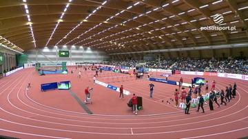 Hala lekkoatletyczna z bieżnią i płotkami, na kt&oacute;rej odbywają się zawody. Widać zawodnik&oacute;w i widz&oacute;w.