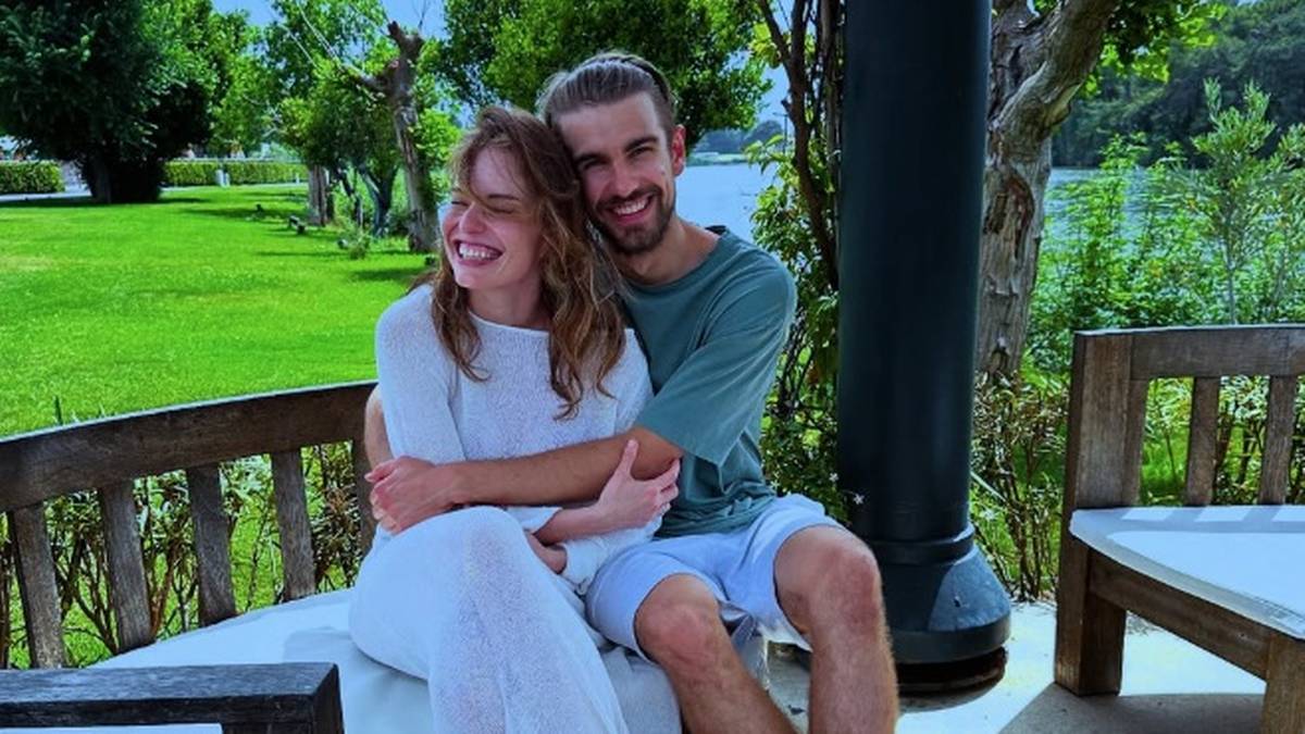 Para siedząca na ławce, mężczyzna obejmuje kobietę.