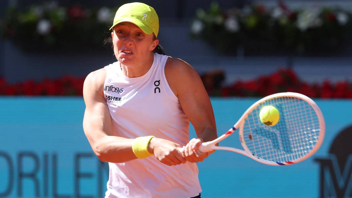 Iga Świątek gra w tenisa, trzyma rakietę i celuje w piłkę.