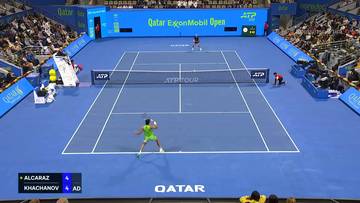 Widok z g&oacute;ry na kort tenisowy podczas meczu Carlosa Alcaraza z Karenem Khachanovem. Zawodnicy są w akcji, a na tablicy wynik&oacute;w widać wynik.