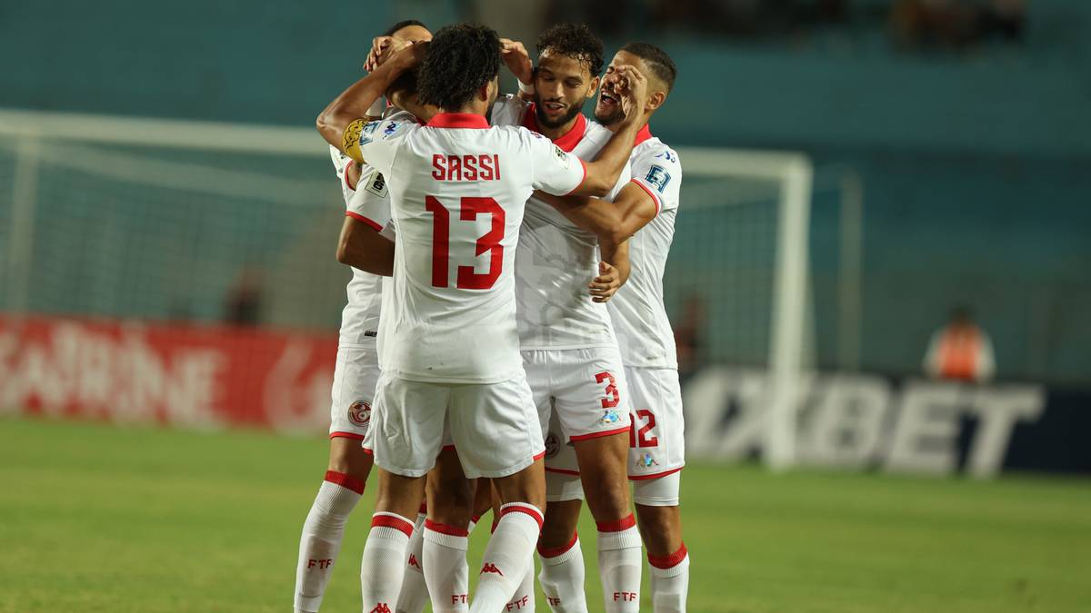 Piłkarze Tunezji w białych strojach świętują zdobycie gola, otoczeni wokół siebie.