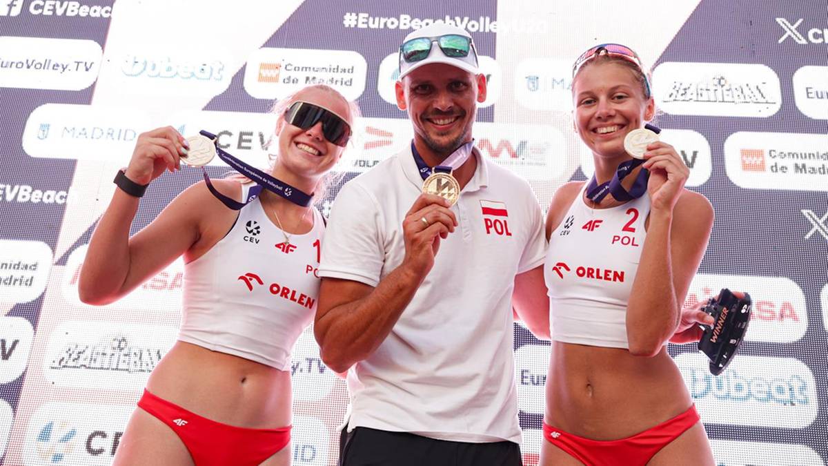Trzy uśmiechnięte osoby trzymające złote medale po wygranej w europejskich rozgrywkach siatkówki plażowej. Dwie kobiety w strojach sportowych i jeden mężczyzna w koszulce z polską flagą.