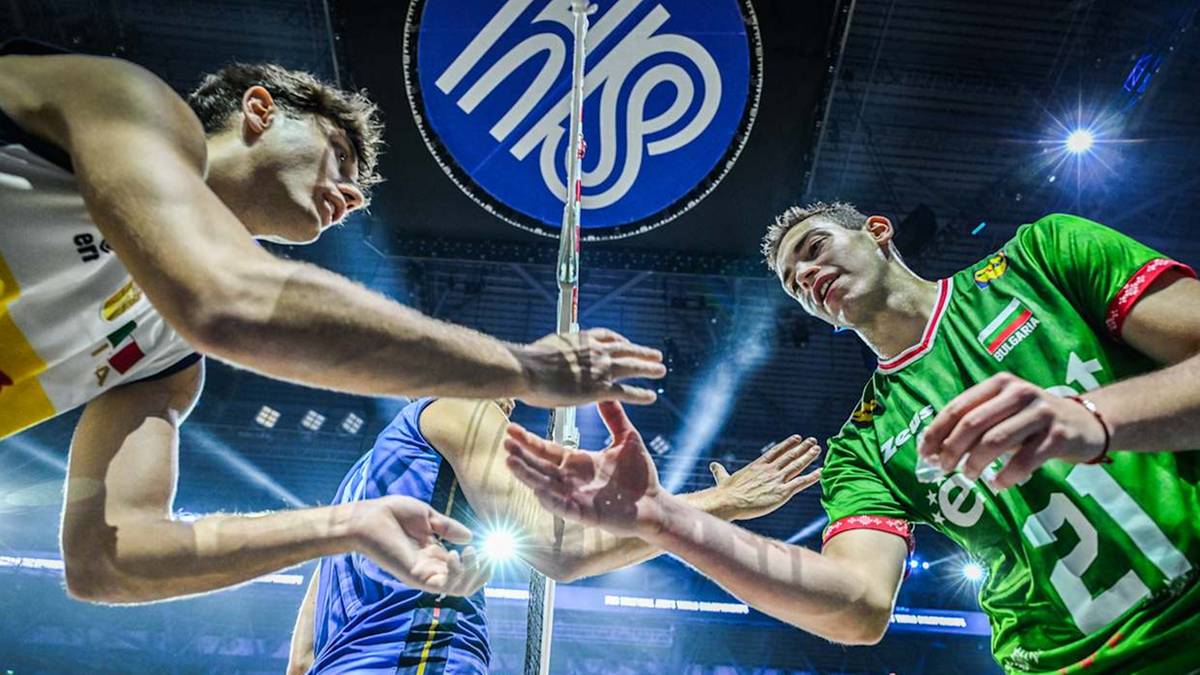 Dwóch siatkarzy w akcji podczas meczu. Jeden w białej koszulce z żółtymi elementami, drugi w zielonej koszulce z numerem 21.