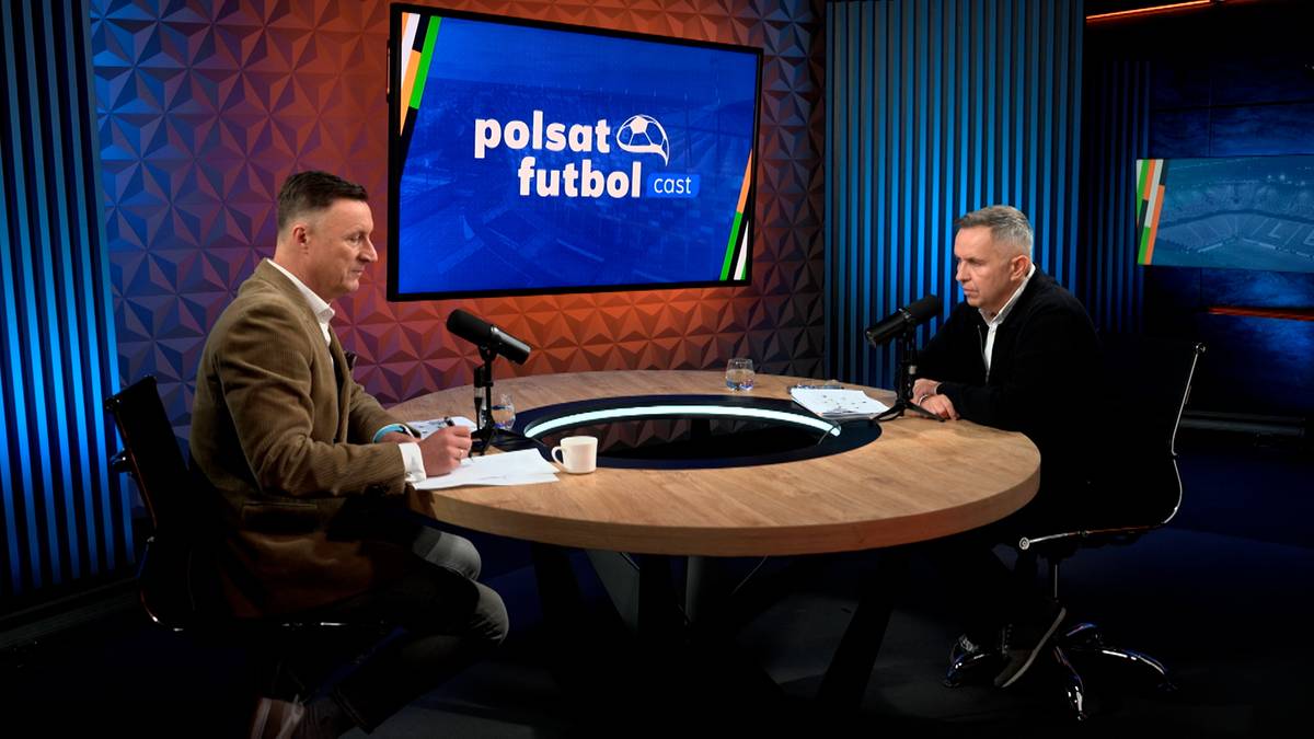 Dwóch mężczyzn siedzi przy okrągłym stole w studiu telewizyjnym i rozmawia. Na ekranie za nimi widnieje logo "polsat futbol".