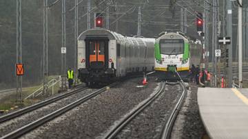 Dwa pociągi na torach kolejowych, z sygnalizacją świetlną w tle.