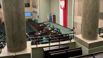 Widok na salę sejmową z rzędami siedzeń i mównicą.