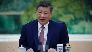 Portret Xi Jinpinga, prezydenta Chin, siedzącego przy stole podczas spotkania.