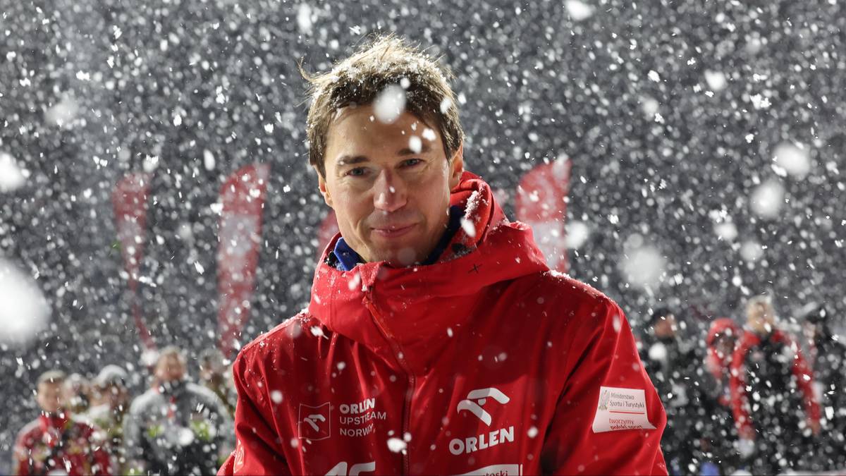 Portret skoczka narciarskiego w czerwonej kurtce podczas zawod&oacute;w w trudnych warunkach pogodowych.