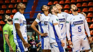 Drużyna Volei Renata w białych strojach z niebieskimi wstawkami patrzy w g&oacute;rę.