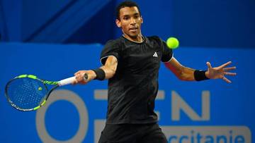 Felix Auger-Aliassime, tenisista, podczas meczu odbija piłkę rakietą.