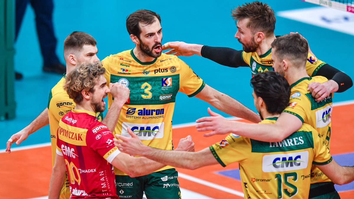 Siatkarze w żółtych koszulkach świętują sukces, przytulając się i unosząc ręce w geście radości po wygranym meczu.