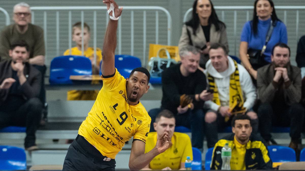 Siatkarz w ż&oacute;łtej koszulce z numerem 9 wykonuje zagrywkę podczas meczu.