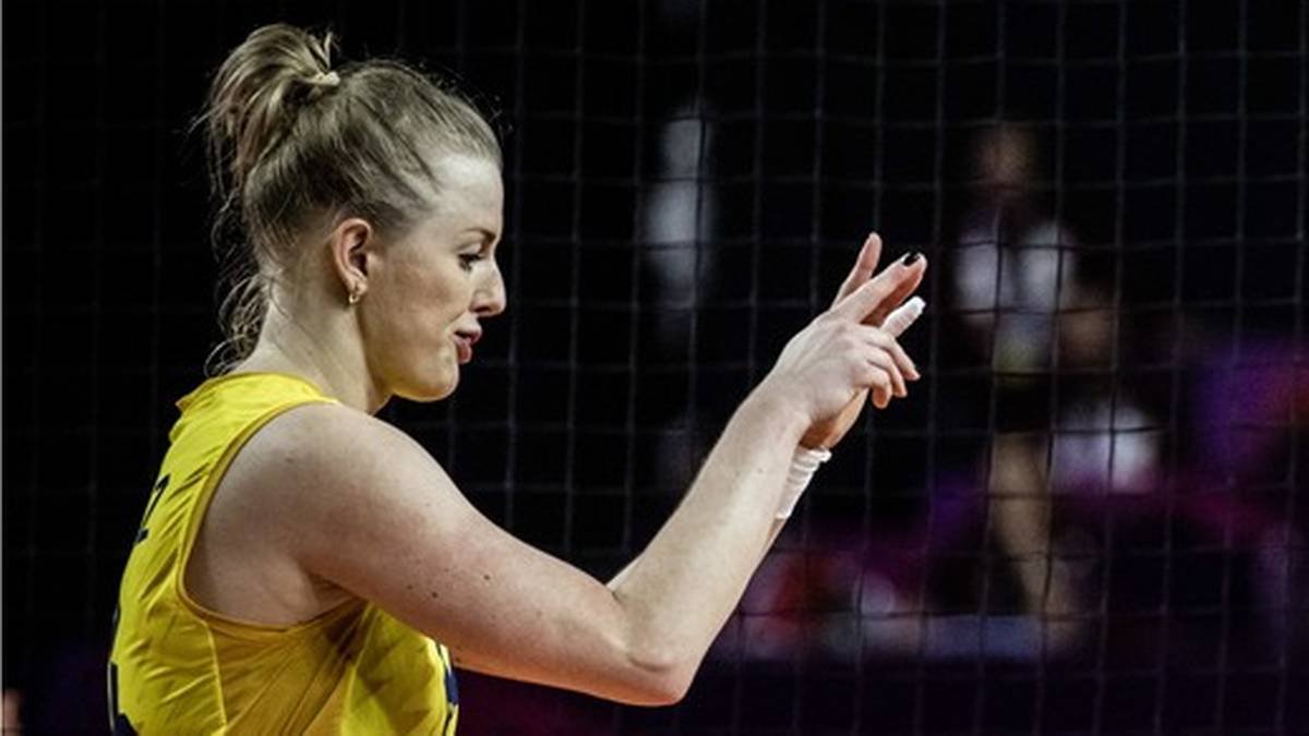 Dwie siatkarki w ż&oacute;łtych strojach sportowych na boisku, jedna z nich pokazuje palcami liczbę dwa, druga krzyczy.