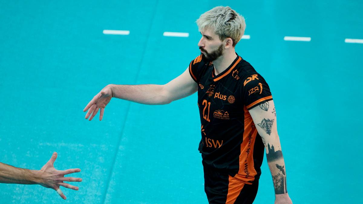 Siatkarz Tomasz Fornal w czarno-pomarańczowej koszulce z numerem 21 wykonuje zagrywkę.