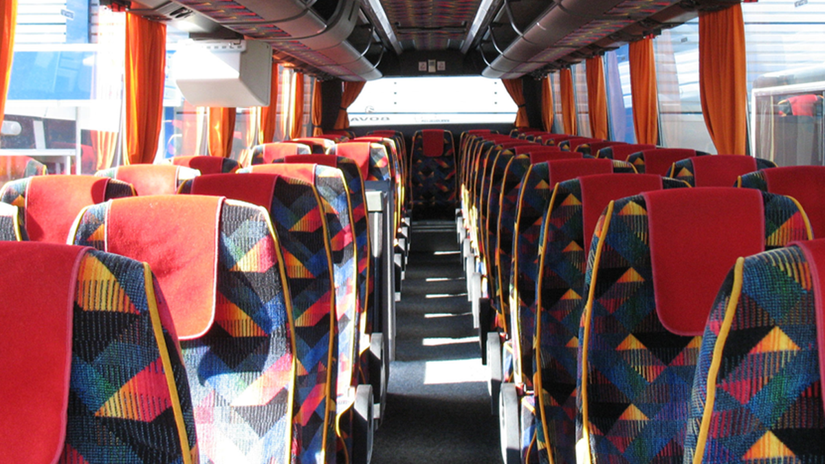Wnętrze autokaru z rzędami kolorowych siedzeń.