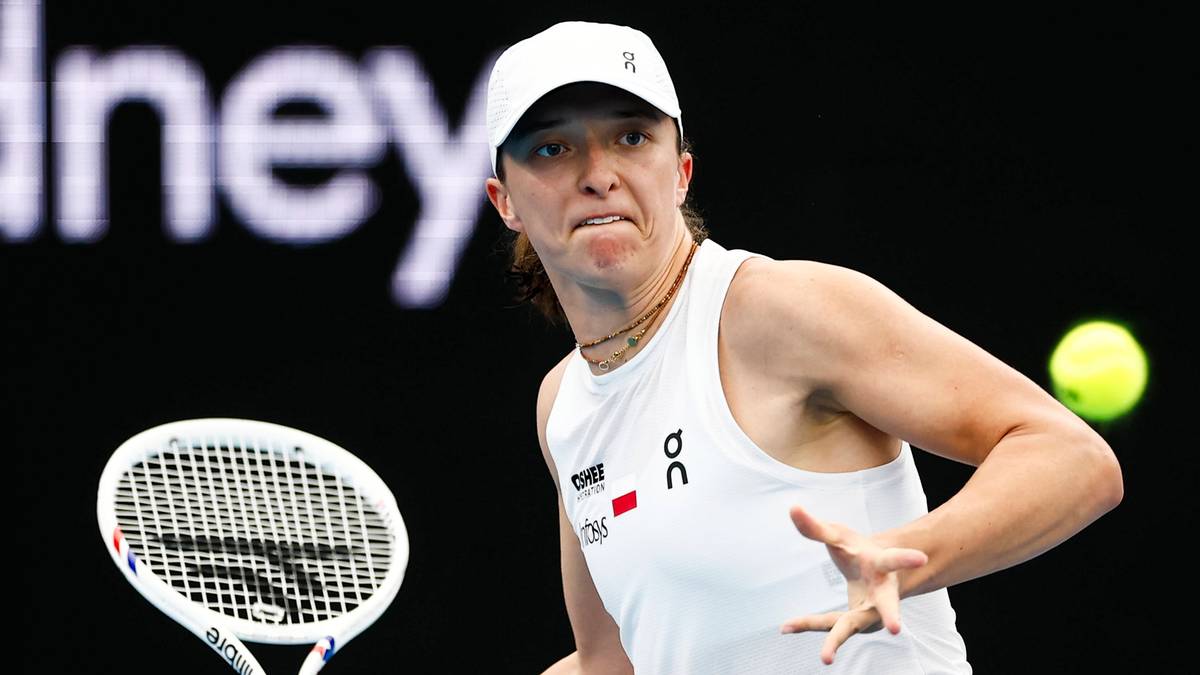 Iga Świątek podczas meczu tenisowego, przygotowująca się do uderzenia piłki.