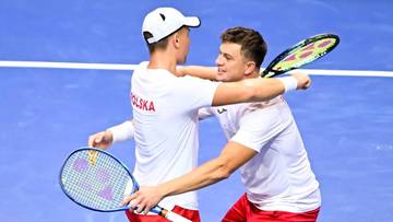 Dw&oacute;ch tenisist&oacute;w w biało-czerwonych strojach z rakietami tenisowymi obejmuje się na korcie.