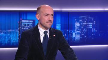 Mężczyzna w garniturze na tle nocnego miasta.