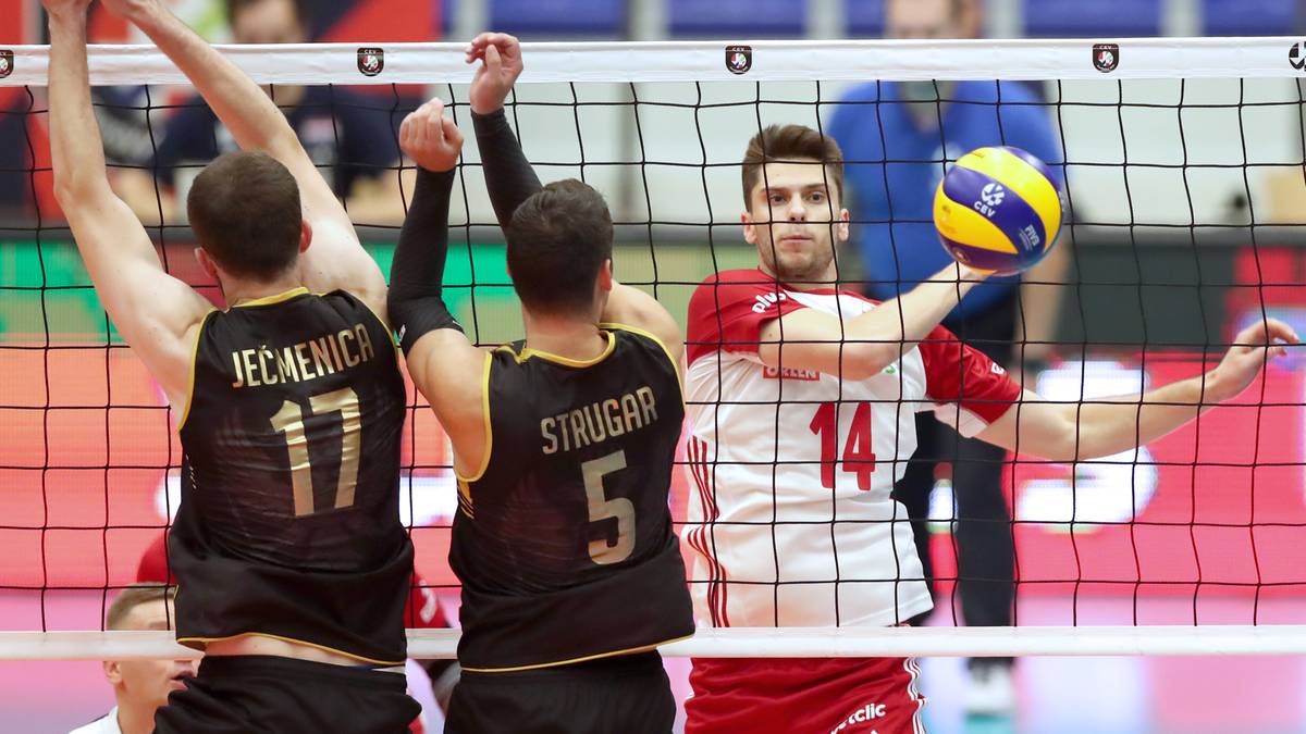 Siatkarze podczas akcji przy siatce, jeden z nich atakuje piłkę.
