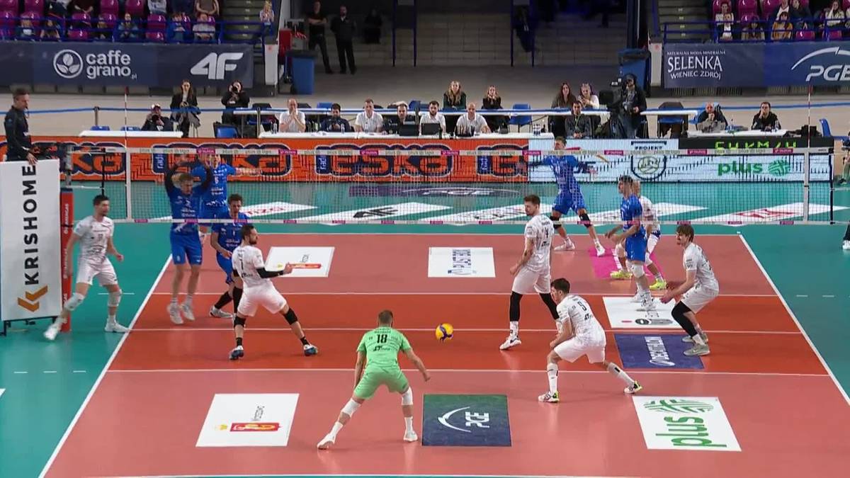 Siatkarze w akcji podczas meczu, jeden z nich pr&oacute;buje zablokować atak przeciwnika.